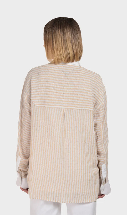 Direct back view showing the relaxed fit, back pleat detail, and horizontal striped yoke on a women's beige dobby fabric long-sleeve shirt.