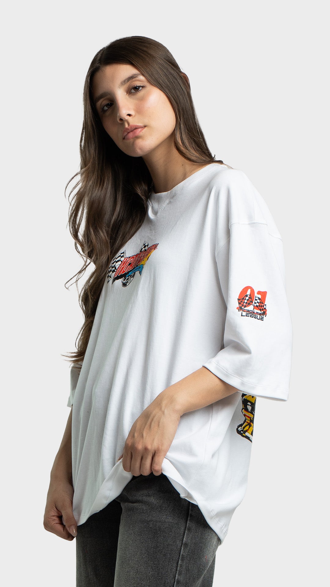 Model posing in an oversized white graphic tee and dark grey jeans.