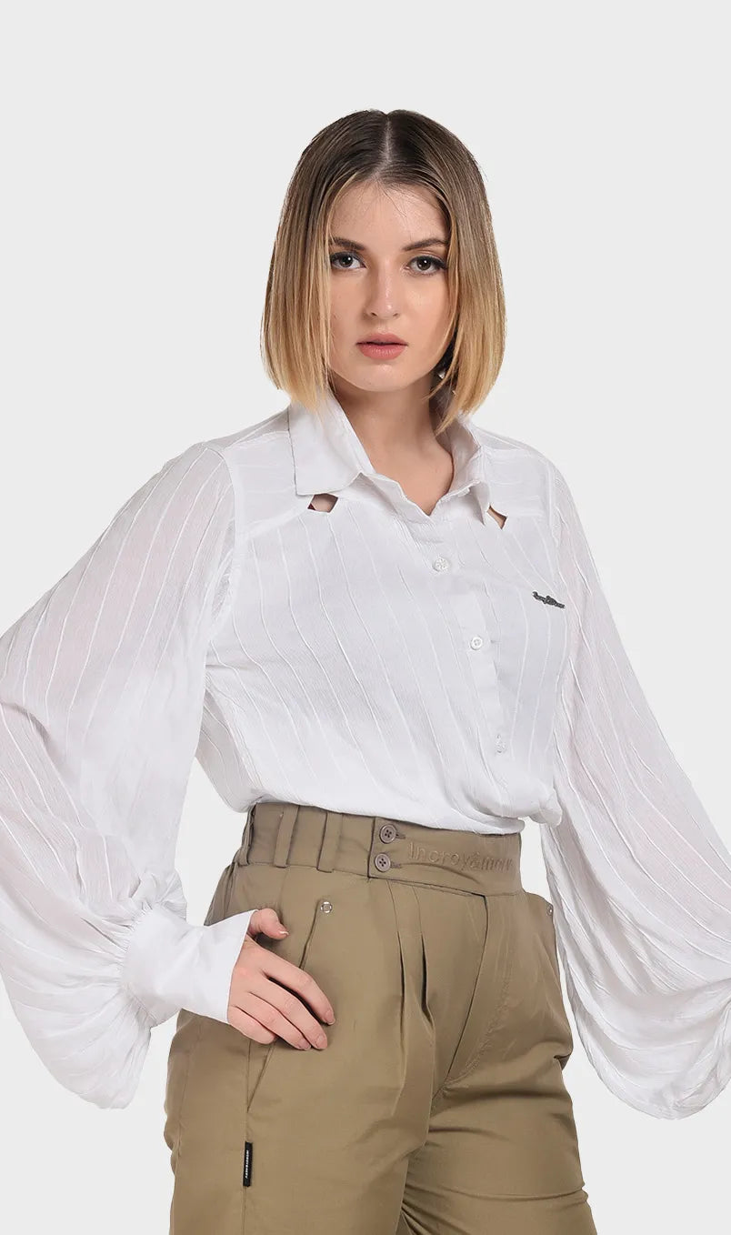 Three-quarter angle view of a model wearing a white rayon shirt with puffy long sleeves tucked into khaki trousers.