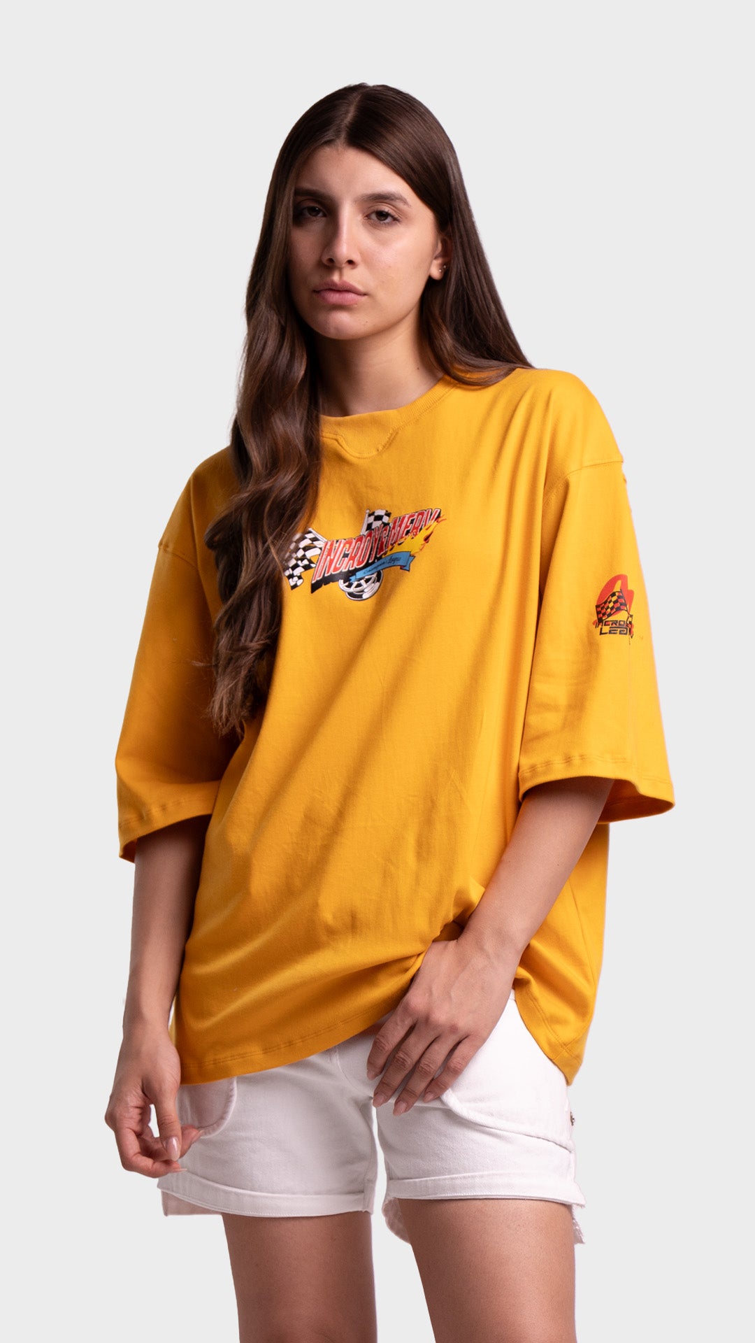 Woman wearing a yellow oversized streetwear t-shirt with a small retro chest graphic and white shorts